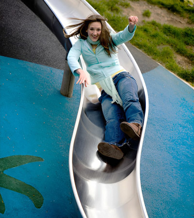 An adult woman going down a slide